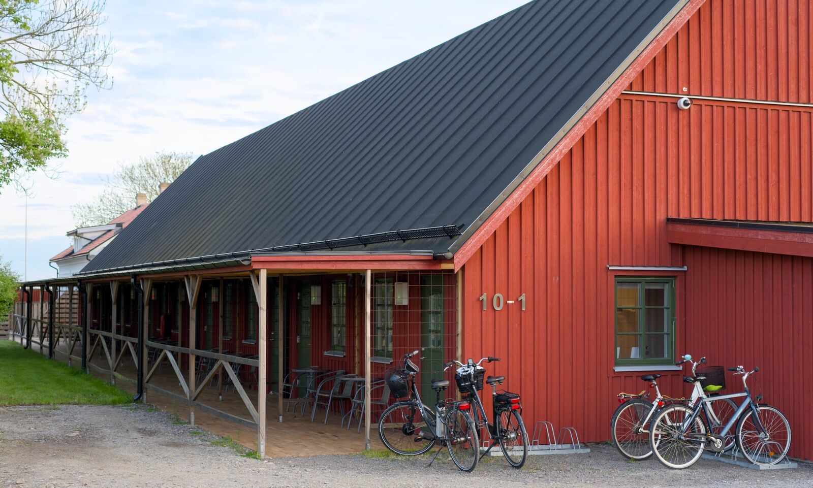 Röd rumslänga med svart tak, veranda och cyklar