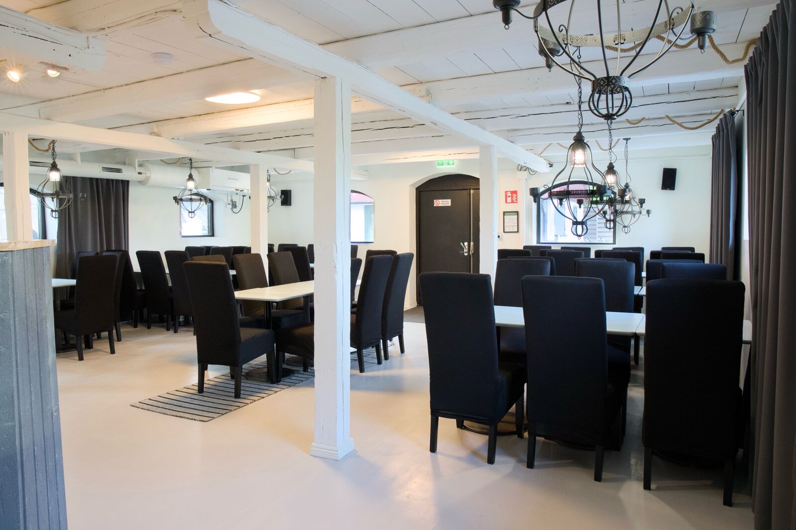 Festsalen med vita träbjälkar, ljuskronor och dukade bord