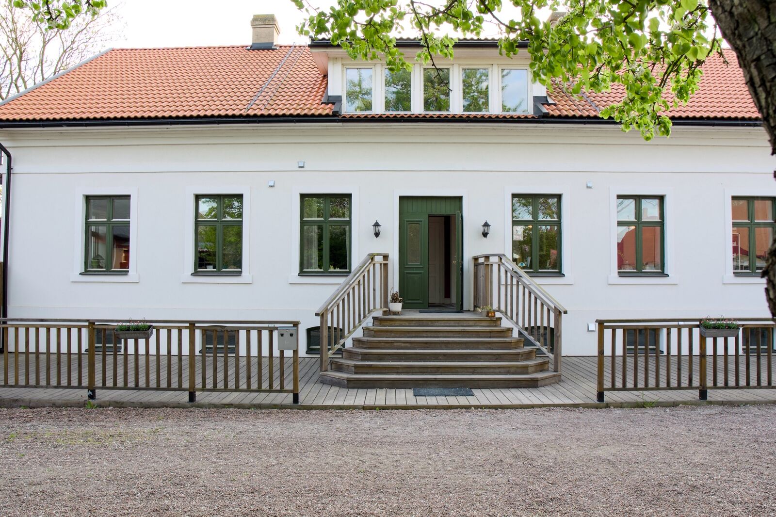 Den vita mangårdsbyggnaden med trappa och veranda