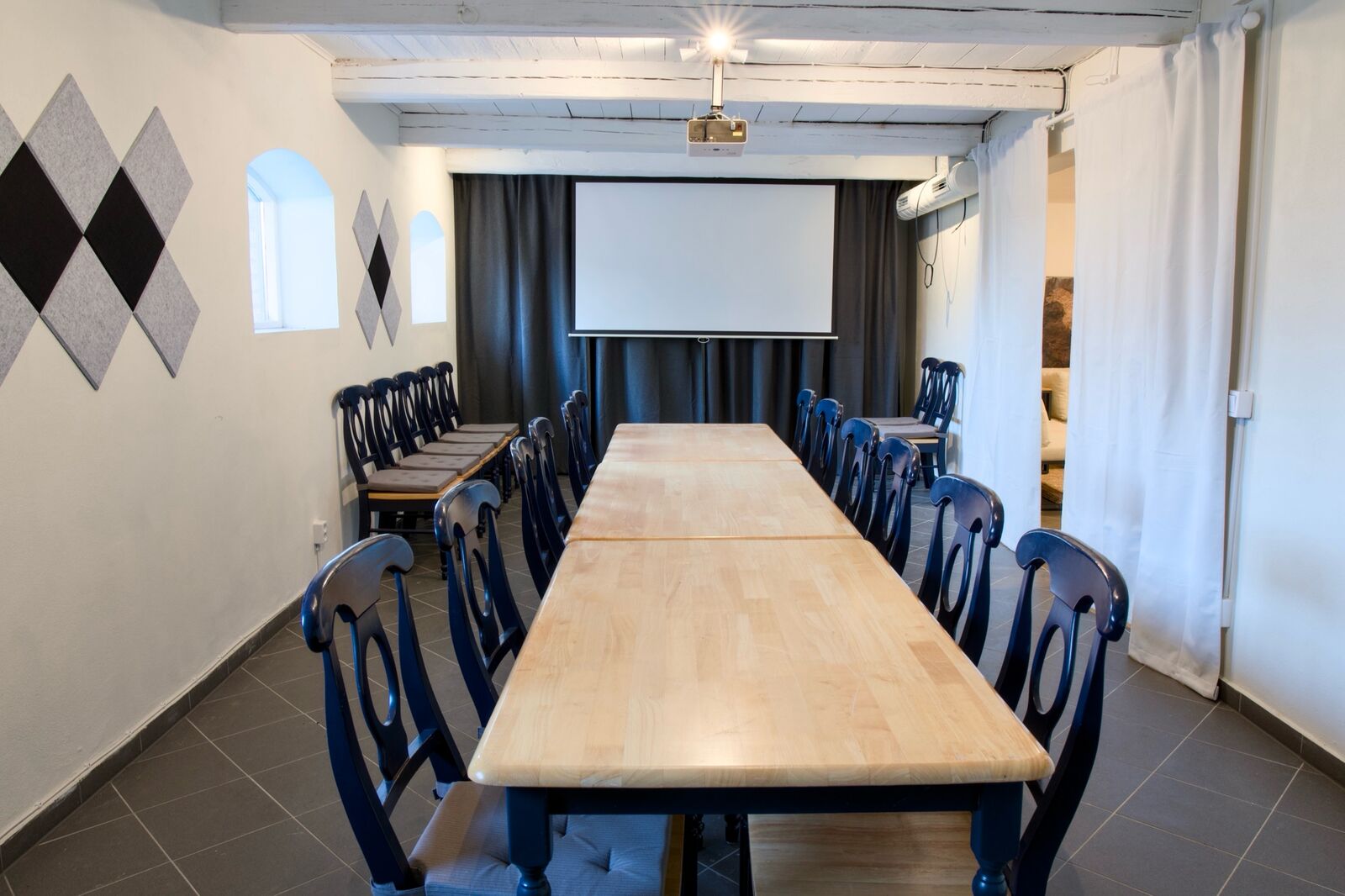 Konferensrum med långbord i trä och projektorduk
