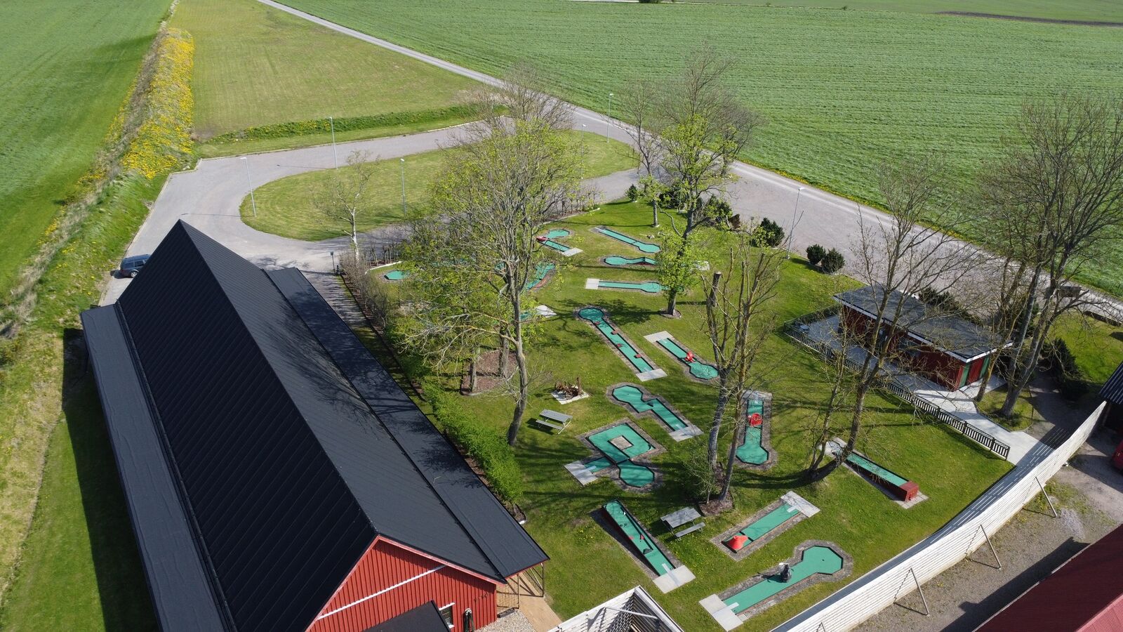 Minigolfbanan bland träden, sedd från ovan med åkrarna runt omkring