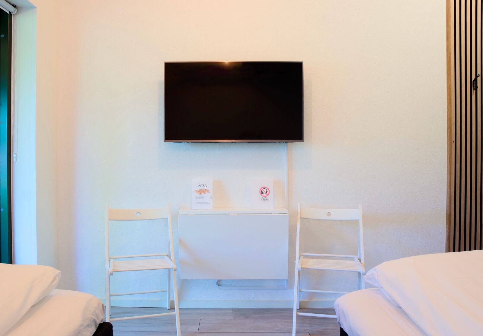 Väggmonterad tv och litet bord med stolar i rummet